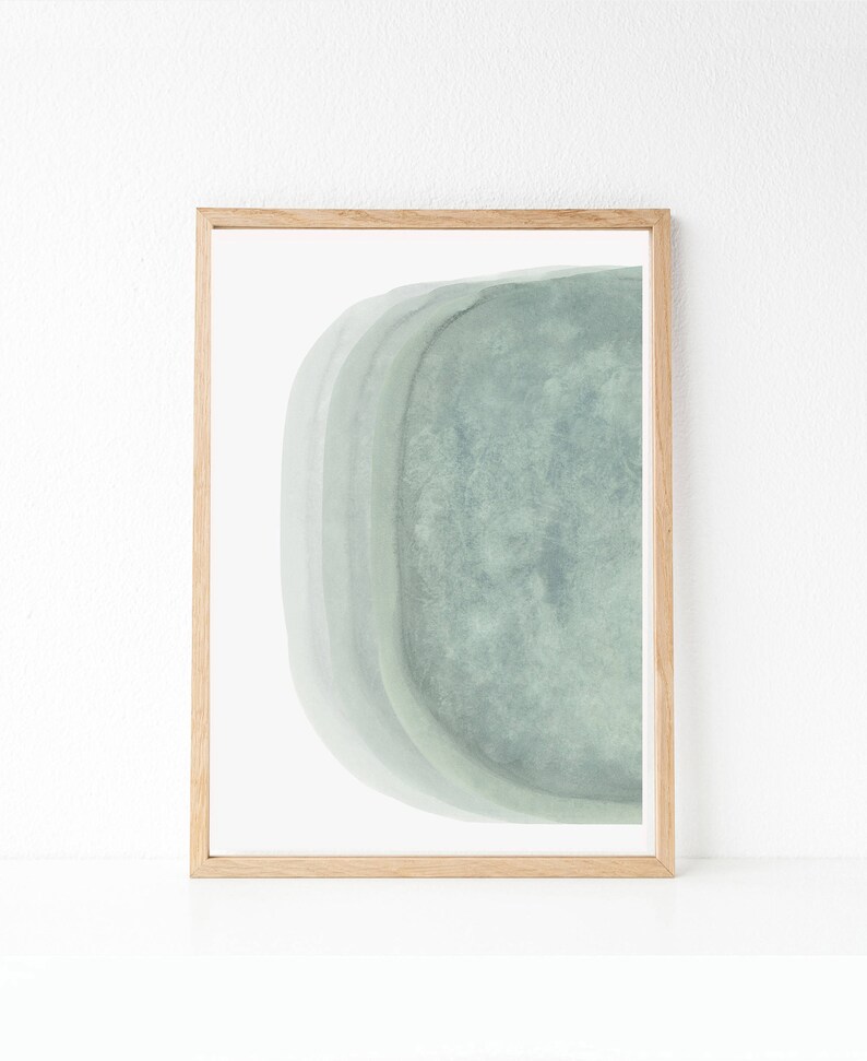May include: A framed abstract art print with a light green watercolor design. The design features a curved shape with layers of color.