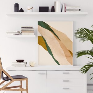 K&ouml;nnte beinhalten: Eine wei&szlig;e Kommode mit drei Schubladen und einer einzelnen T&uuml;r. Die Kommode hat silberne Griffe. Ein gerahmtes abstraktes Kunstbild mit gr&uuml;nen, braunen und beigefarbenen Farben h&auml;ngt &uuml;ber der Kommode. Ein Holzstuhl mit schwarzem Sitz steht vor der Kommode.