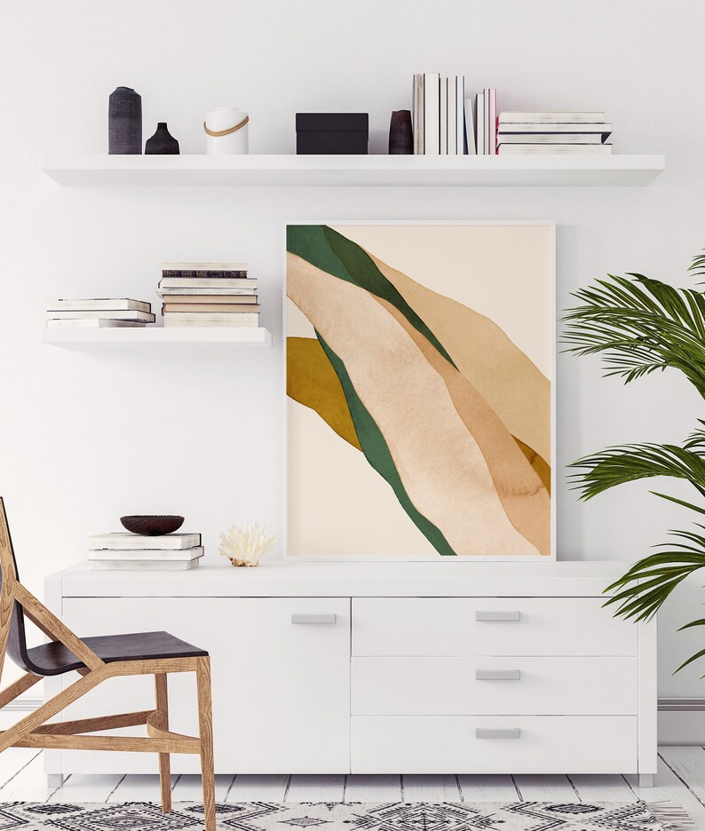 K&ouml;nnte beinhalten: Eine wei&szlig;e Kommode mit drei Schubladen und einer einzelnen T&uuml;r. Die Kommode hat silberne Griffe. Ein gerahmtes abstraktes Kunstbild mit gr&uuml;nen, braunen und beigefarbenen Farben h&auml;ngt &uuml;ber der Kommode. Ein Holzstuhl mit schwarzem Sitz steht vor der Kommode.