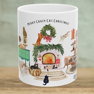 May include: White ceramic mug with a Christmas scene featuring cats. The mug has the text "Merry Crazy Cat Christmas!" printed on it. The scene includes cats decorating a Christmas tree, sitting by a fireplace, and playing with ornaments.