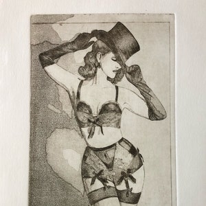 May include: A black and white etching print depicting a woman in lingerie, a top hat, and long gloves. The artwork is titled "Jénas 1900" at the bottom. The woman is posed with one arm raised, and the style is vintage.
