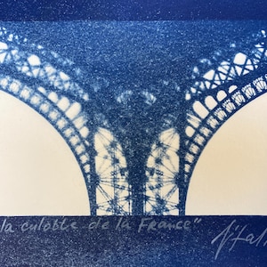 May include: A cyanotype print of the Eiffel Tower in Paris, France. The image is a close-up of the top of the tower, showing the intricate metalwork. The print is signed "la culotte de la France" and "J. Hall".
