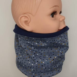Könnte beinhalten: Ein blauer und weißer gemusterter Halsschmeichler mit marineblauem Saum. Der Halsschmeichler ist aus weichem, dehnbarem Stoff gefertigt und perfekt, um sich im Winter warm zu halten.