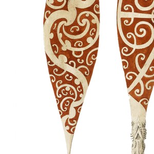 Puede incluir: Dos palas de madera marr&oacute;n y blanco con punta puntiaguda. Las palas tienen un dise&ntilde;o tradicional con remolinos blancos sobre un fondo marr&oacute;n.