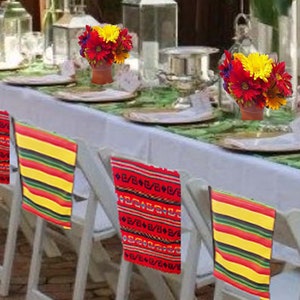 May include: A white tablecloth with red and yellow striped chair backs covers a table set for a party.  The table is decorated with yellow and red flowers in small pots and lanterns.