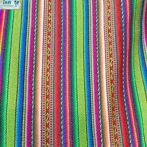 Puede incluir: Una tela tejida que presenta un patrón de rayas verticales repetitivas en colores vibrantes que incluyen verde lima, azul brillante, magenta, naranja, rojo y blanco. El diseño incorpora líneas geométricas finas e intrincadas y bandas sólidas.
