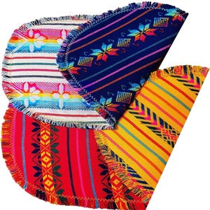 May include: A collection of colorful, half-circle woven placemats. Each mat features a unique pattern, including stripes, geometric designs, and floral motifs. The mats have fringed edges and a vibrant color palette of red, blue, yellow, and rainbow hues.