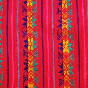 May include: Red fabric with a repeating pattern of blue, yellow, and green geometric shapes. The fabric has a striped background.