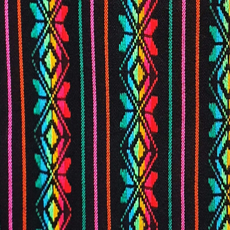 May include: Close-up of a black fabric with a vibrant, colorful pattern. The design features vertical stripes in orange, pink, and green, interspersed with repeating geometric floral motifs in red, yellow, blue, and green.