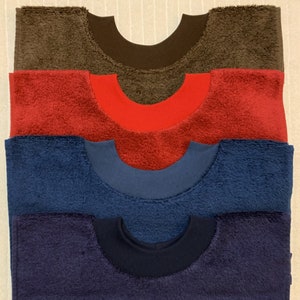 May include: Four terry cloth bibs in different colors: brown, red, blue, and navy blue. Each bib has a contrasting color trim around the neck.
