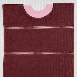 May include: A burgundy terry cloth bib with pink trim and three horizontal stripes of white, pink, and green.