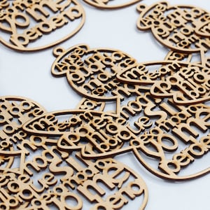 May include: A collection of circular brown wooden laser-cut ornaments featuring the Spanish text "Si me pierdo" and "A veces guapa, a veces no" arranged in a decorative typography style. Each piece includes a small hole at the top for hanging.