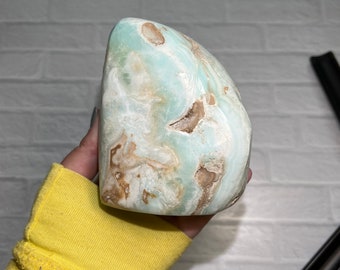 May include: A large, light blue and brown, irregularly shaped, polished, natural stone. The stone has a swirling pattern and a smooth, polished surface.