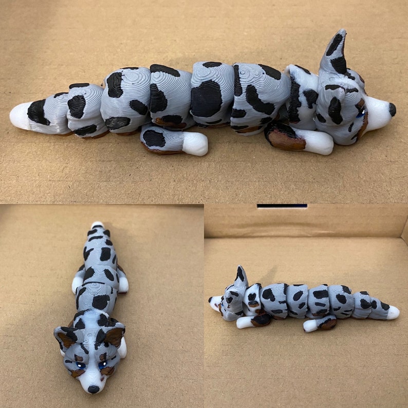 May include: A segmented, gray and black, 3D printed dog figurine. The dog is lying on its side with its head resting on its paws. The figurine is made up of several pieces that are connected together.