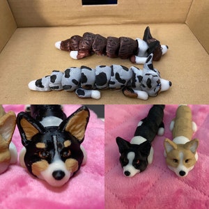 May include: Three different 3D printed dog figurines. The first is a brown and black dog with a segmented body. The second is a gray and black dog with a segmented body. The third is a black and white dog with a solid body.