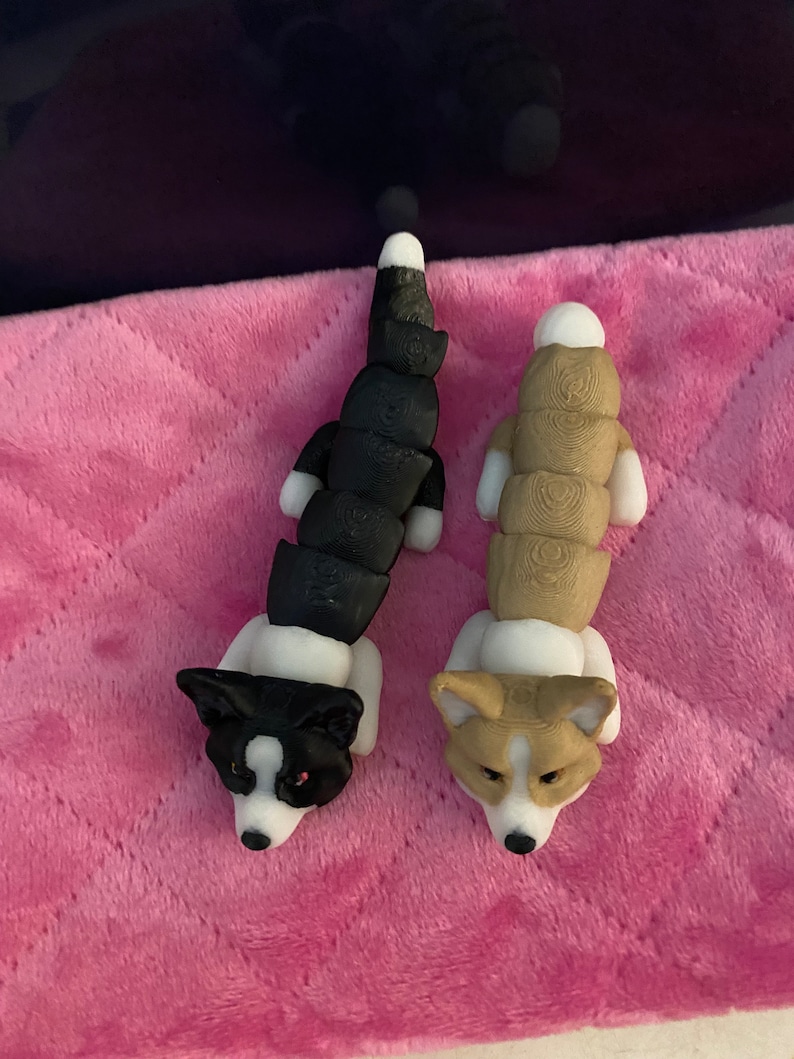 May include: Two small, segmented, plush dog toys. The dog on the left is black and white, and the dog on the right is brown and white.