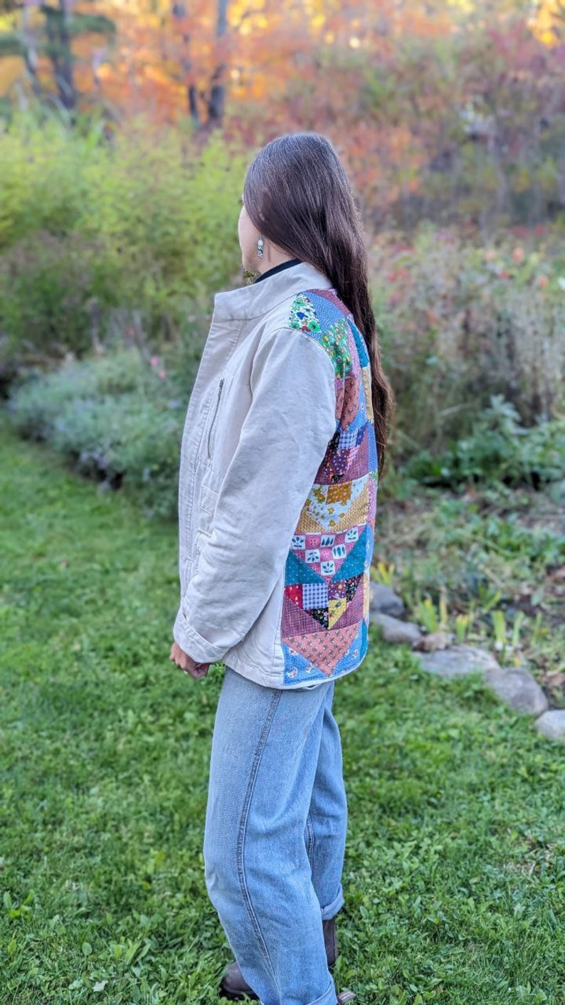 May include: A beige jacket with a patchwork design on the back. The jacket is made of a soft, comfortable fabric and has a relaxed fit. The patchwork design is made up of different colored fabrics, including blue, green, red, and yellow.