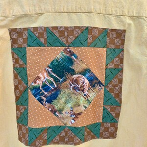 Puede incluir: Una camisa amarilla de botones con un dise&ntilde;o de patchwork marr&oacute;n y verde en la espalda. El patchwork presenta un cuadrado con un estampado de ciervo en el interior.