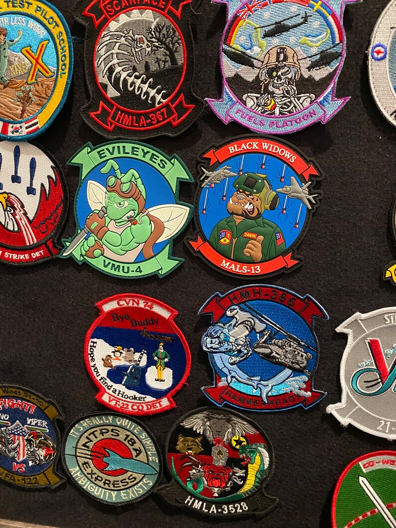Może przedstawiać: Kolekcja haftowanych naszywek z r&oacute;żnymi odznakami jednostek wojskowych, w tym "Black Widows", "EVILEYES", "HMLA-367", "HMH-366", "VT-22 CO DET", "HMLA-3528", "VMU-4", "MALS-13", "FUELS PLATOON", "STRIKE DET", "HAMMERHEADS", "TPS 18A EXPRESS", "BYO BUDDY", "SCAREFACE" i "TEST PILOT SCHOOL".