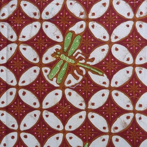 Könnte beinhalten: Nahaufnahme eines gemusterten Stoffes mit einem sich wiederholenden Design aus weißen Ovalen und roten floralen Akzenten auf einem dunkelroten Hintergrund. Eine grüne und gelbe Libelle ist in der Mitte des Bildes zu sehen.