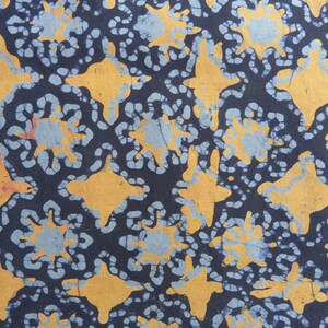 May include: A fabric with a repeating pattern of blue and yellow shapes. The shapes are abstract and resemble flowers or stars.