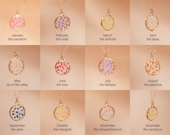 May include: Twelve gold necklaces with round pendants featuring pressed flowers. Each pendant represents a different month of the year and flower. The pendants are clear and show the flowers in their natural colors.