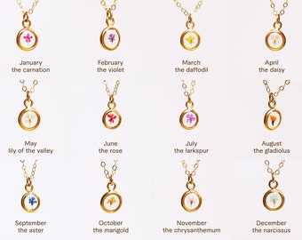 May include: Twelve gold necklaces with a small round pendant featuring a pressed flower inside. Each necklace represents a month of the year and features a different flower. The flowers are: carnation, violet, daffodil, daisy, lily of the valley, rose, larkspur, gladiolus, aster, marigold, chrysanthemum, and narcissus.