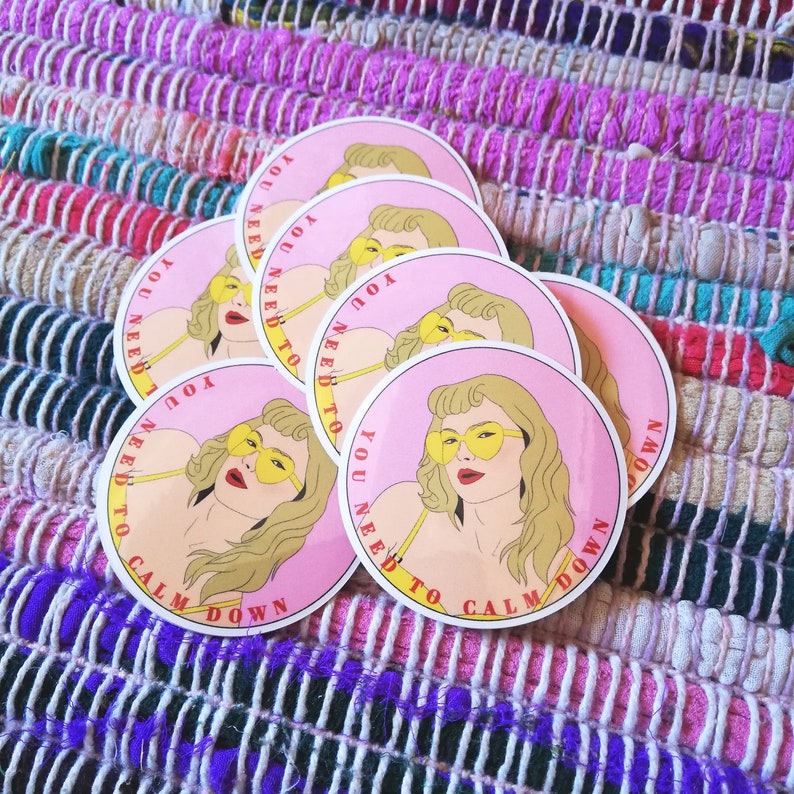 May include: Five pink and white round stickers with a woman's face and the text "You need to calm down" in red and yellow lettering.