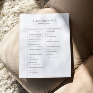 May include: A white paper titled "Super Simple SEO Squarespace Checklist" with bullet points for internal and external SEO strategies. The paper is on a beige surface.