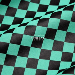 May include: A close-up shot of a fabric featuring a black and teal chequered design. The material is folded, revealing its texture and how it drapes. The text "FO:REST FABRICS" is visible in the lower centre.