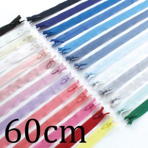 May include: A collection of 60 cm zippers in various colors, including black, white, pink, purple, red, and yellow. The zippers are arranged diagonally, showcasing their different shades. The image features the text "60 cm" in black.