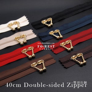 May include: Assortment of 40cm double-sided zippers with gold metal slider pulls and decorative beads. The zippers are in various colours including beige, red, brown, navy blue, and black.