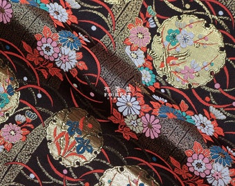 May include: Black fabric with a gold and red floral pattern. The fabric features a repeating design of stylised flowers and leaves. The fabric is woven with a textured surface.