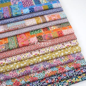 Pode incluir: Uma pilha de tecidos florais coloridos. Os tecidos apresentam uma variedade de padrões, incluindo designs de patchwork e pequenas estampas florais em tons de azul, rosa, vermelho e amarelo. O texto "www.forestfabrics.com" e "TO BE ST" é visível.