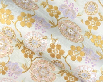 May include: White fabric with a repeating pattern of gold, pink, and purple flowers. The fabric has a textured, woven look.
