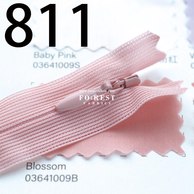May include: A close-up of a baby pink zipper with a matching fabric swatch. The zipper is open, revealing the teeth and slider. The fabric swatch is a lighter shade of pink. The number "811" is printed in black at the top of the image.