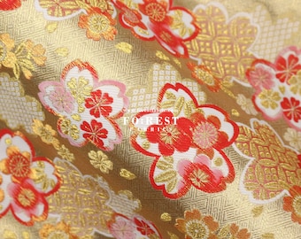 May include: Gold fabric with a repeating pattern of red, pink, and white flowers. The fabric has a subtle sheen and a textured surface.