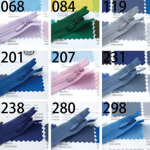 May include: A collection of various colored zippers, each with a unique color name and number. Colors include shades of blue, green, pink, and gray. Each zipper is displayed with a swatch of matching fabric.