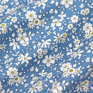 May include: Blue fabric with a white floral pattern. The fabric is covered in small white flowers with yellow centers.