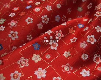 May include: Red fabric with a repeating pattern of white and gold flowers and a gold diamond pattern. The fabric has the text "布 惑星" (meaning "Fabric Planet") and "FOREST FABRICS" printed on it.