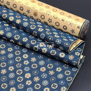 Puede incluir: Dos rollos de tela con un patrón floral azul y dorado. La tela está doblada y los bordes son visibles. La tela está etiquetada con "FOREST FABRICS" y "www.forestfabric.com".