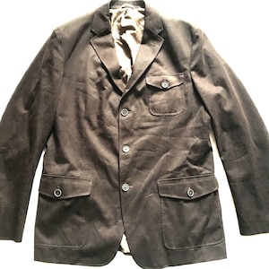 May include: A dark brown blazer with a classic design. The jacket features a notched lapel, three buttons, and two front pockets with button closures. The interior lining is a lighter brown color.