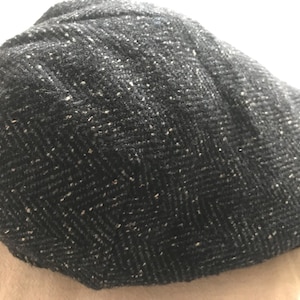 May include: A black and white herringbone patterned newsboy cap.