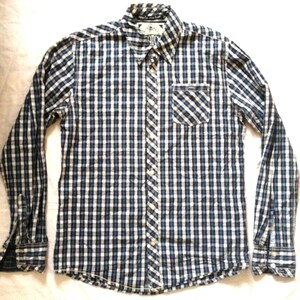 May include: A long-sleeved button-down shirt with a blue and white checkered pattern. The shirt has a button-down collar, a chest pocket, and buttoned cuffs. The shirt is made of a lightweight fabric.