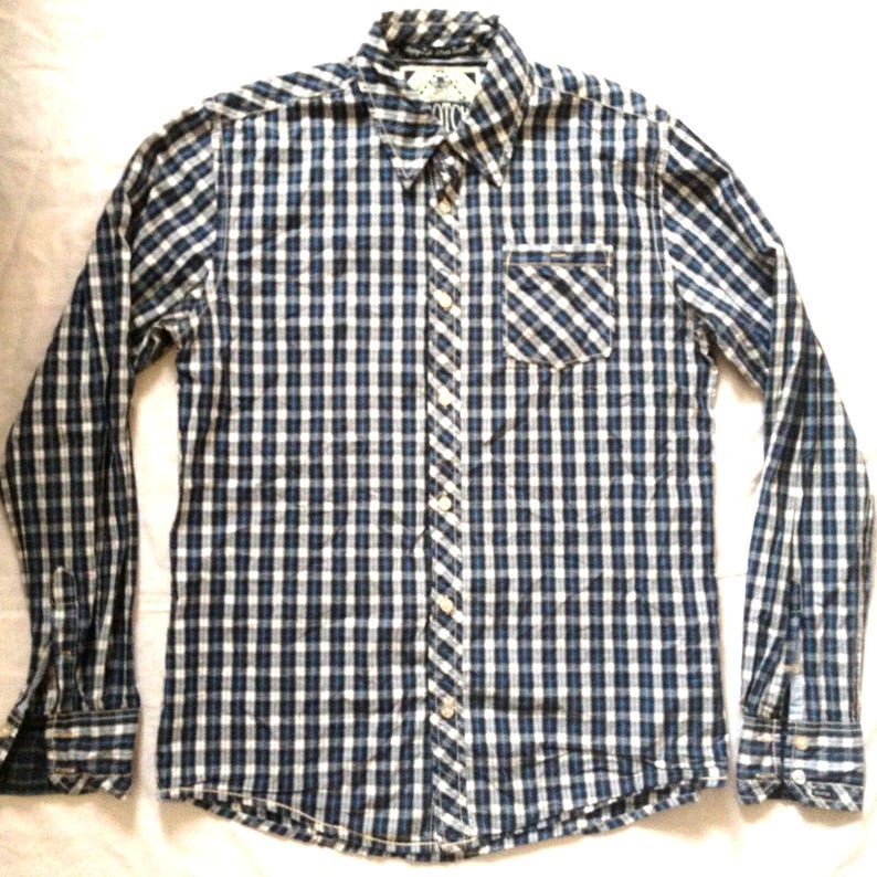 May include: A long-sleeved button-down shirt with a blue and white checkered pattern. The shirt has a button-down collar, a chest pocket, and buttoned cuffs. The shirt is made of a lightweight fabric.