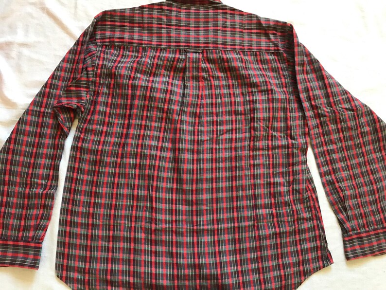 Puede incluir: Camisa de manga larga a cuadros rojos, negros y grises. La camisa tiene un dise&ntilde;o cl&aacute;sico con botones, cuello y pu&ntilde;os. El estampado de cuadros es un dise&ntilde;o tradicional, adecuado para ropa informal.