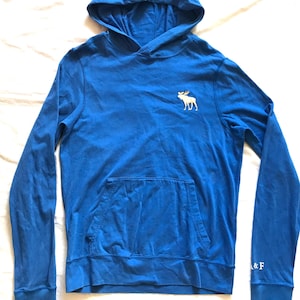 May include: A blue hooded sweatshirt with a kangaroo pocket and long sleeves. A white moose logo is on the upper left chest. The letters "& F" are on the right sleeve cuff.