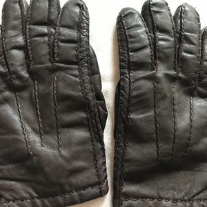 Puede incluir: Un par de guantes de cuero marrón con un diseño cosido. Los guantes están hechos de cuero suave y flexible y tienen un aspecto clásico.