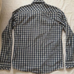 May include: A long-sleeved button-down shirt with a blue and white checkered pattern. The shirt has a classic collar and buttoned cuffs. The fabric appears to be a lightweight cotton or blend, suitable for casual wear.