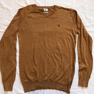 May include: A brown long-sleeve v-neck sweater with a small embroidered logo on the chest.
